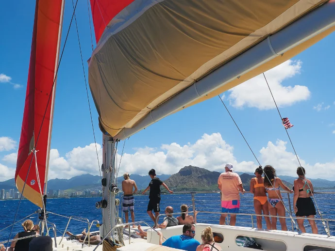 Guests on deck under full sail with Diamond Head on the horizon