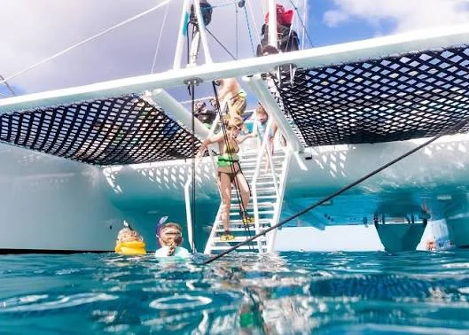 Snorkellers in the water beside the catamaran’s boarding ladder