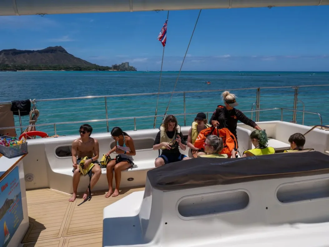 Guests aboard with snorkel gear and vests, Diamond Head across the water