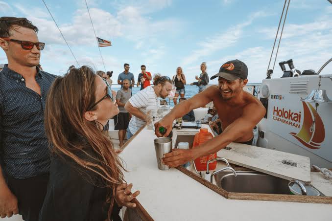 A crewmember pouring a drink at the bar aboard the catamaran